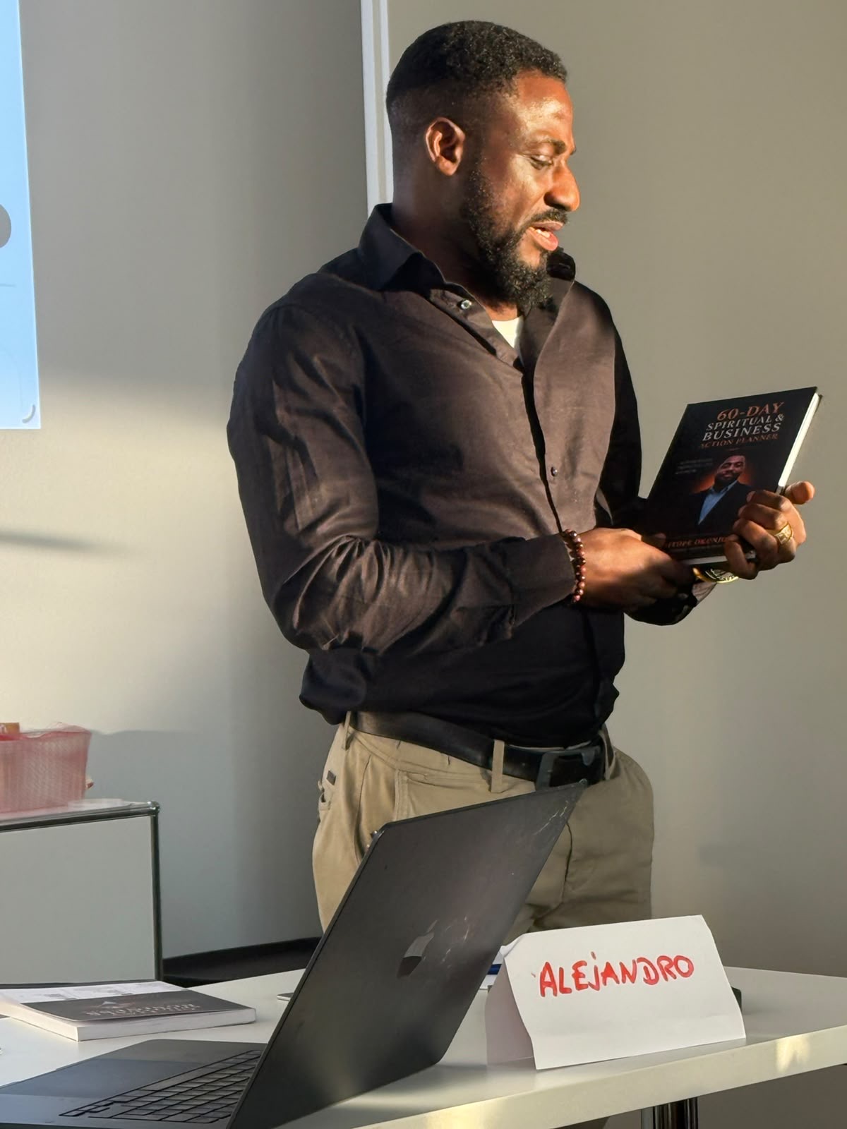 Temitope Okunjolu speaking, holding his book